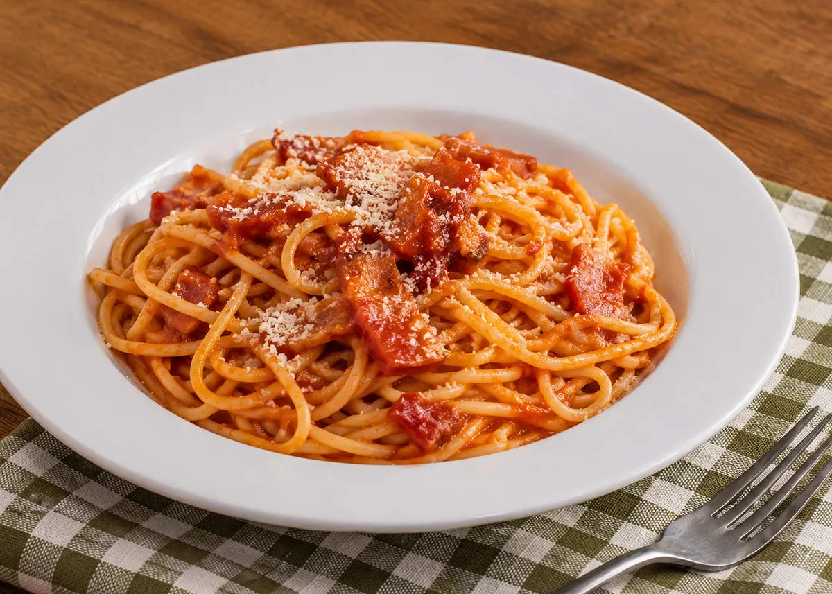 Spaghetti all'Amatriciana with tomato sauce, guanciale and grated pecorino on a white plate